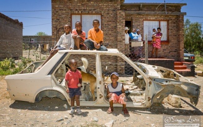 Boys playing in shell and roof of scrapped car