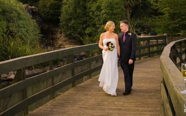 married couple talking and strolling across wooden bridge